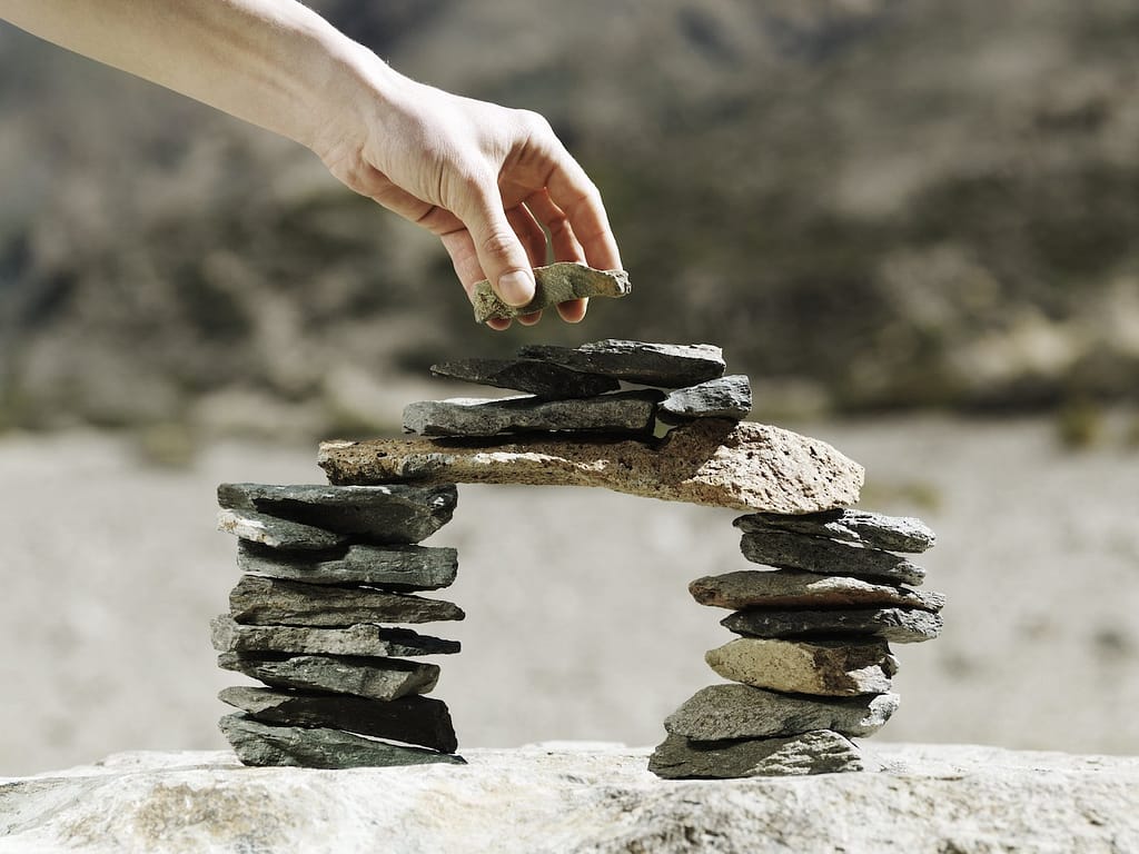 La pierre finale est placée à la main sur un pont modèle miniature d'équilibrage fait de petits rochers plats à l'extérieur